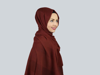 Portrait of young woman standing against white background