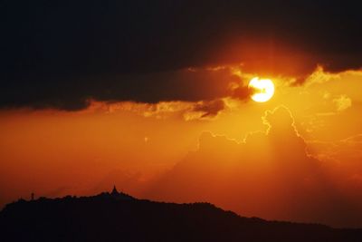 Scenic view of mountains against cloudy sky at sunset