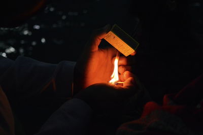 Close-up of man holding lit candles