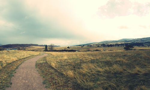 Road amidst field against sky