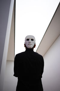 Low angle portrait of man standing against wall