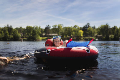 Portrait of girl in inflatable ring on river against sky