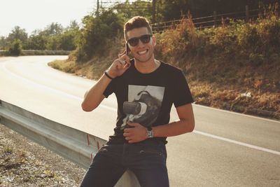 Portrait of man wearing sunglasses while talking on mobile phone in city