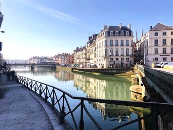 Bridge over canal amidst buildings in city against sky