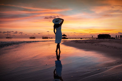 Full length of woman standing on beach during sunset