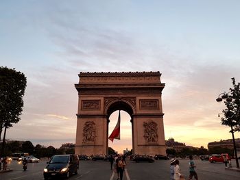 People walking in front of historic building against sky