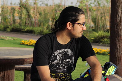 Young man looking away while sitting outdoors