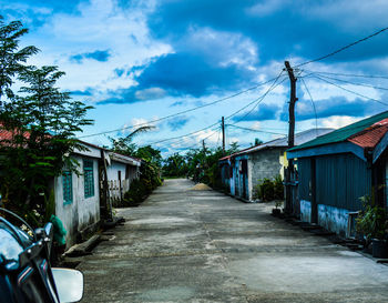 Street amidst trees against sky