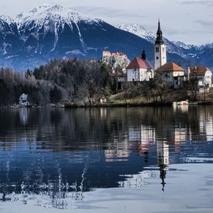 Scenic view of lake by building against mountain during winter