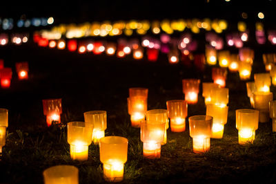 Close-up of lit candles on a field at night