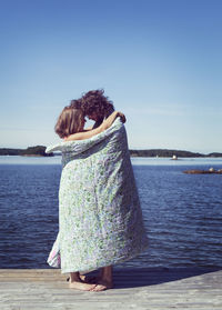 Couple wrapped in towel embracing on beach