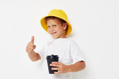 Portrait of smiling boy gesturing while holding bottle against white background