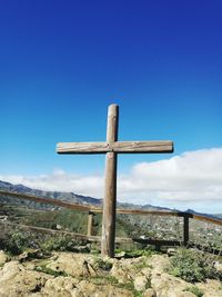 Cross on landscape against blue sky