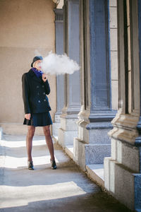 Young woman smoking while standing at corridor