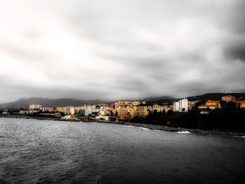 Houses by sea against sky