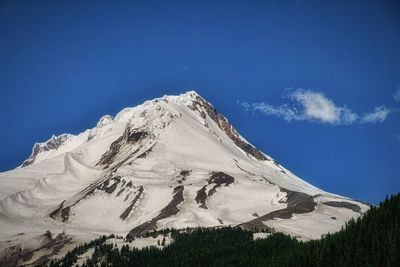 Low angle view of snowcapped mountain against blue sky