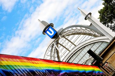 Rainbow flag hanging on railing of underground station against sky