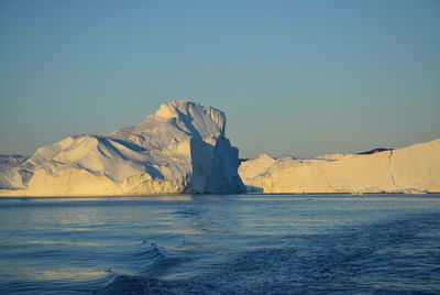 Scenic view of sea against clear sky with beautiful icebergs in the midnight sun ilulissat greenland