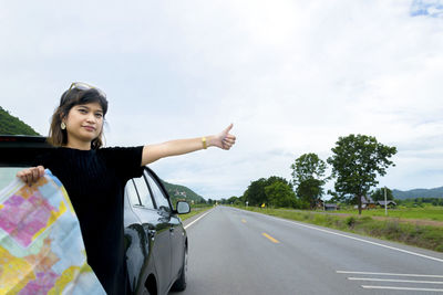 Woman standing on road against sky