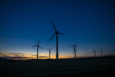 Power generators of windmills at shadow sunset - wind turbine on field at sunset