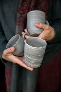 Midsection of person holding mugs