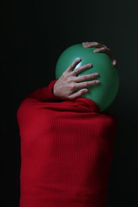 Rear view of person with balloon against black background
