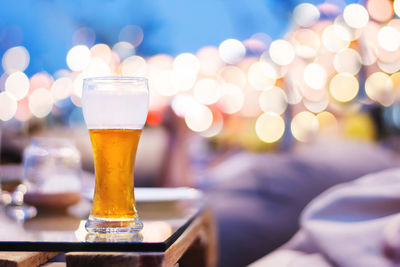Close-up of beer in glass on table against lens flare