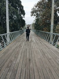 Full length rear view of man walking on bridge
