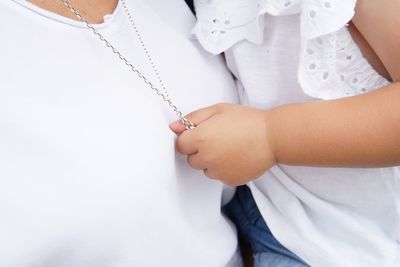 Midsection of mother with daughter holding necklace