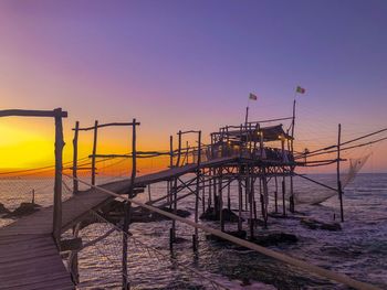 Pier over sea against sky during sunset