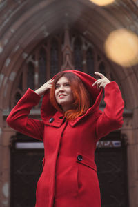 Close up pretty smiling lady in red coat on street portrait picture