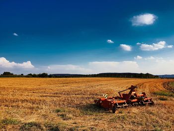 Scenic view of harvester on a field against sky