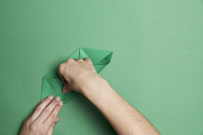 Close-up of hand holding paper against green background