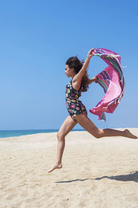 Teenage girl jumping at beach