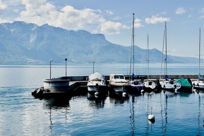 Sailboats moored on lake against sky