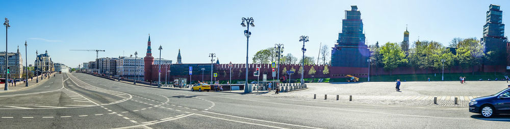 Cars on road by buildings against clear sky