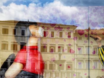 Rear view of woman standing by window against sky