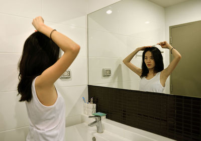 Young woman doing make-up in bathroom