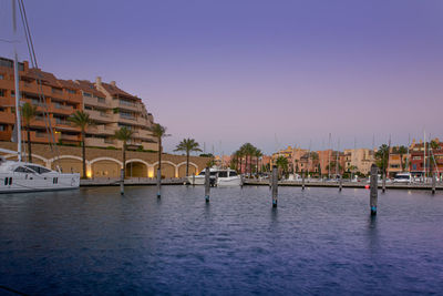 View of river by buildings against blue sky