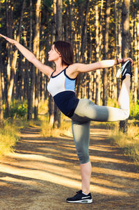 Full length of woman with arms raised in forest