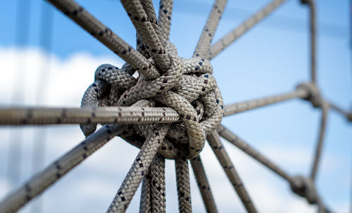 Close-up of rope tied up on railing against sky