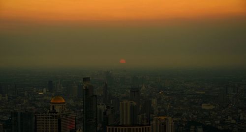 Aerial view of buildings in city during sunset