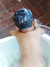Shirtless boy in bathtub at home