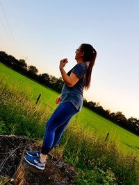 Young woman on field against clear sky