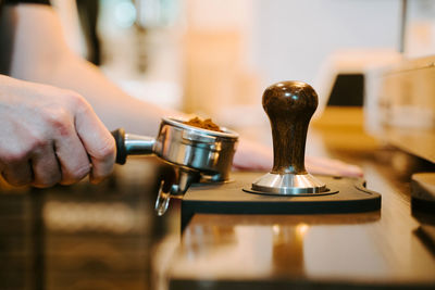 Pile of fresh ground coffee in portafilter placed in modern coffee machine at counter in cafe