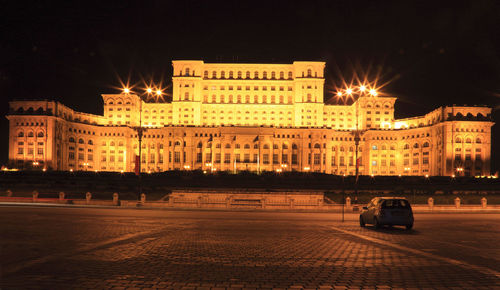 Cars on road by illuminated buildings in city at night