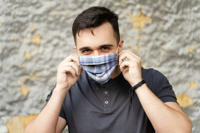 Portrait of young man covering face against wall