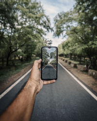 Midsection of person holding smart phone against sky