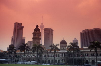 Menara kuala lumpur tower by mosque against sky during sunset