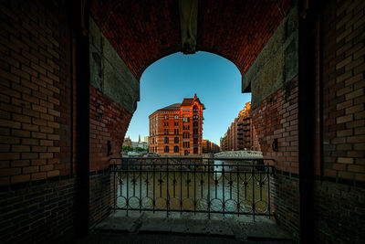 View of buildings against sky seen through gate